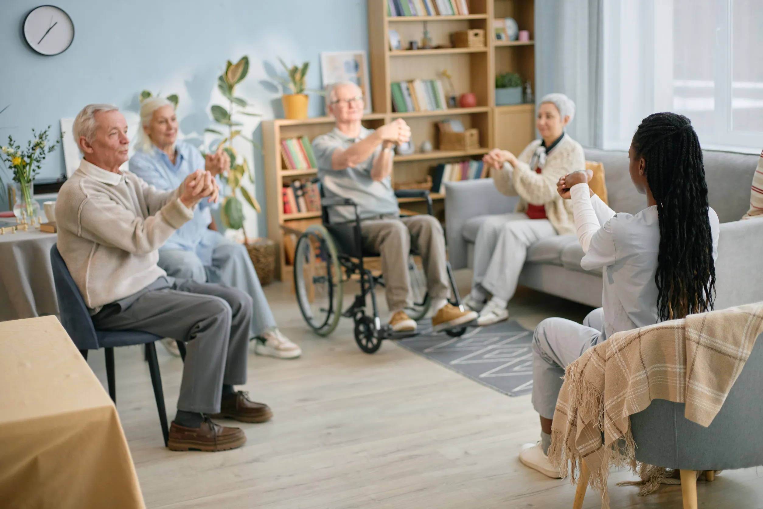 Elderly group engaging in chair exercise session in cozy room, guided by young instructor Elderly group engaging in chair exercise session in cozy room, guided by young instructor