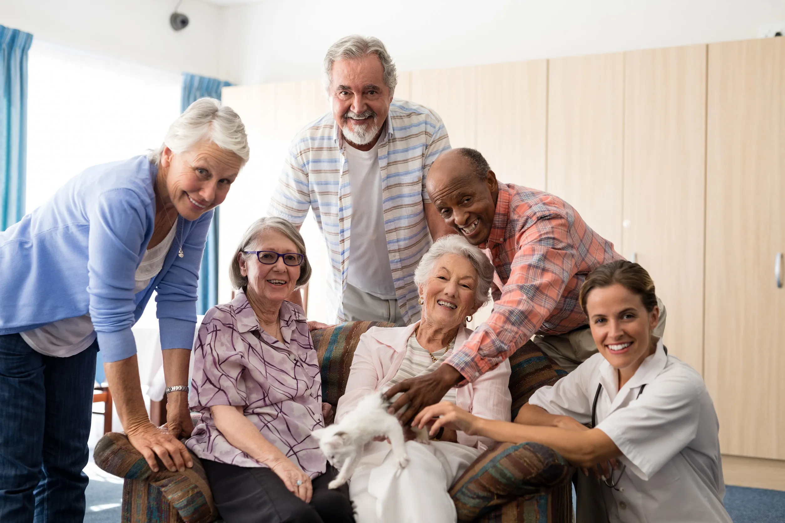 Portrait of female doctor and senior people with kitten at nursing home