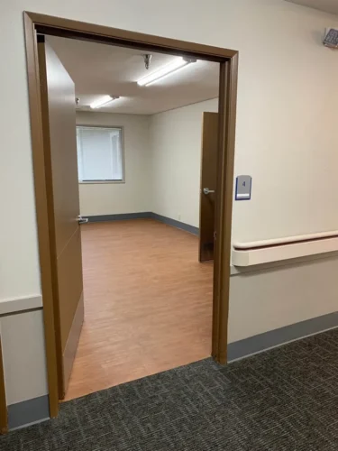 Open doorway leading into an empty room with wooden flooring and a window