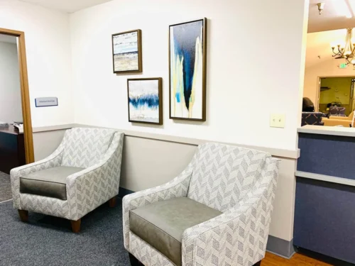 Two patterned chairs sit against a wall adorned with abstract art, next to a doorway labeled Administrator. Cozy and inviting atmosphere